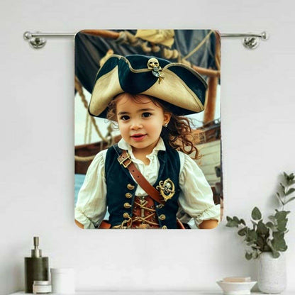 Example of how to upload a toddler girl's photo to create a personalized pirate portrait on a towel featuring her dressed as a pirate on a ship deck.