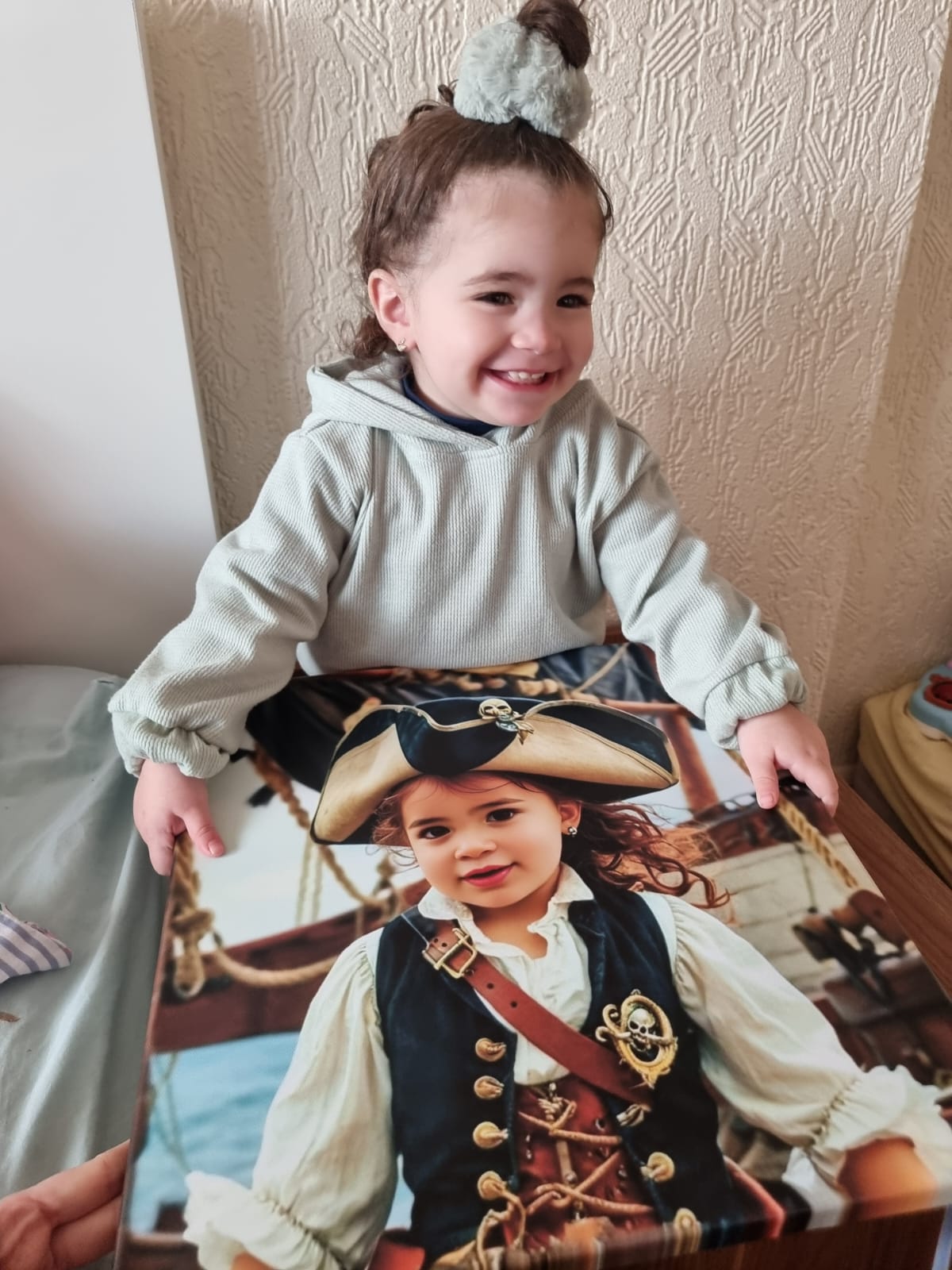 A young girl smiling while holding her personalized pirate portrait canvas, featuring herself dressed as a pirate on a ship deck. The vibrant canvas showcases her custom design, with her image transformed into a pirate character.